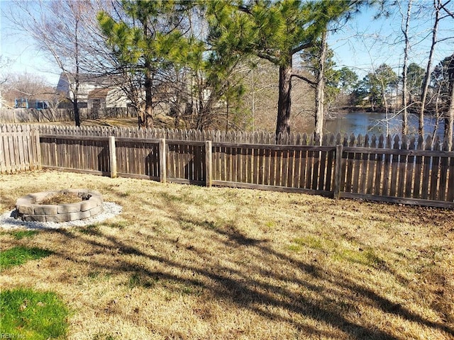 view of yard with a water view, a fire pit, and fence