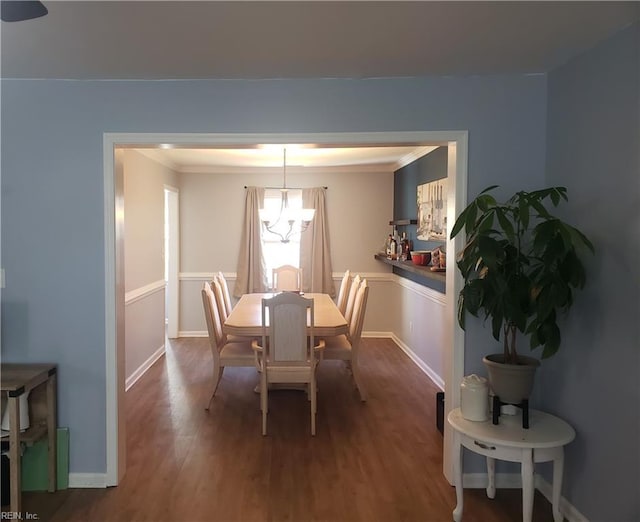 dining area featuring a chandelier, dark wood-type flooring, ornamental molding, and baseboards