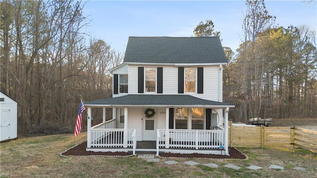 farmhouse with a shingled roof, fence, a porch, and a front yard