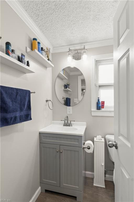 bathroom featuring crown molding, vanity, a textured ceiling, wood finished floors, and baseboards