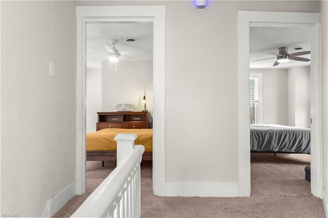 corridor with carpet, a textured ceiling, and baseboards