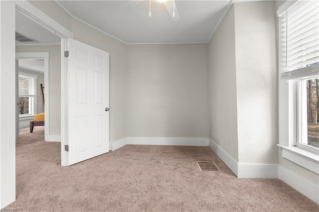 spare room with carpet floors, a healthy amount of sunlight, and visible vents