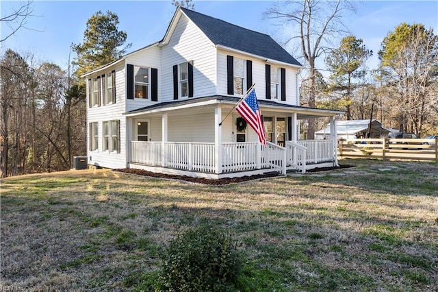 farmhouse-style home with covered porch, fence, and a front lawn