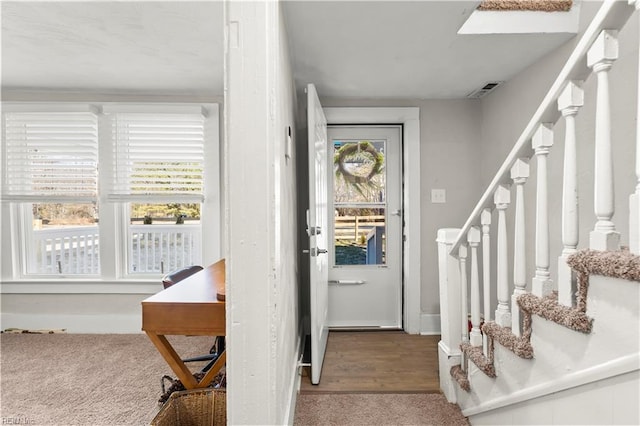 carpeted foyer featuring visible vents and stairway