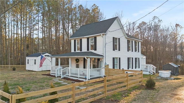 view of front of home featuring covered porch, fence, a storage unit, an outdoor structure, and a front lawn