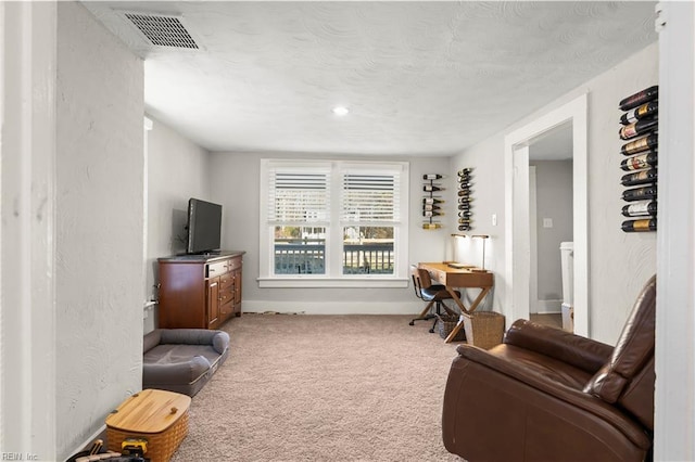 sitting room featuring carpet floors, visible vents, and a textured ceiling