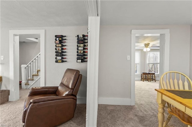 sitting room featuring stairs, carpet, and baseboards