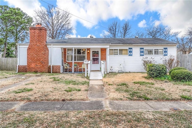 view of front of home with a porch, brick siding, fence, and a chimney