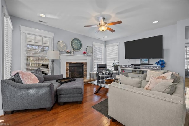 living room with recessed lighting, visible vents, ceiling fan, a stone fireplace, and wood finished floors