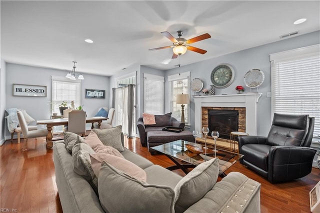 living room with a fireplace, wood finished floors, visible vents, and a ceiling fan