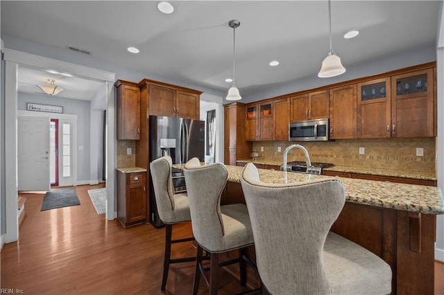 kitchen featuring stainless steel appliances, brown cabinets, visible vents, and dark wood finished floors