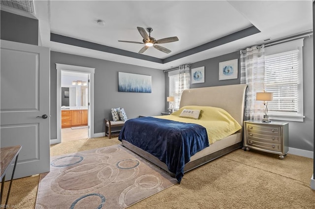 bedroom featuring a raised ceiling, visible vents, light carpet, and baseboards