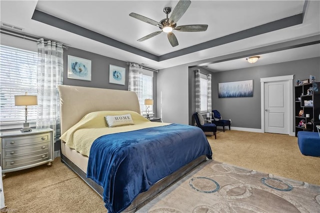 bedroom featuring carpet, a raised ceiling, visible vents, ceiling fan, and baseboards