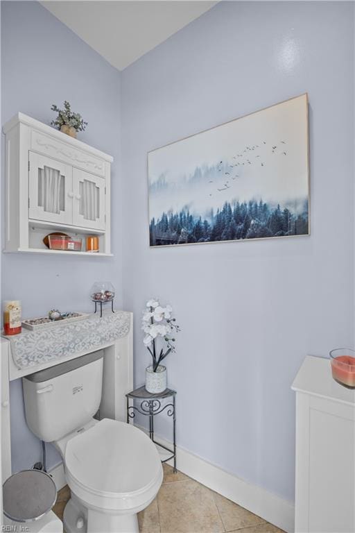 bathroom with toilet, baseboards, and tile patterned floors