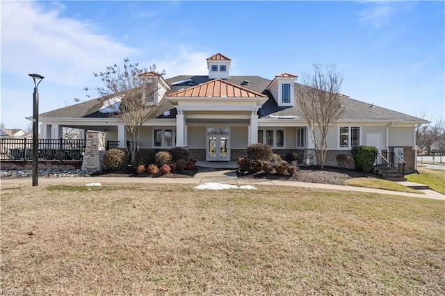 view of front of house with brick siding, fence, a front lawn, and french doors