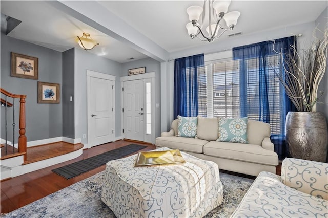 living room featuring baseboards, visible vents, stairway, wood finished floors, and a notable chandelier