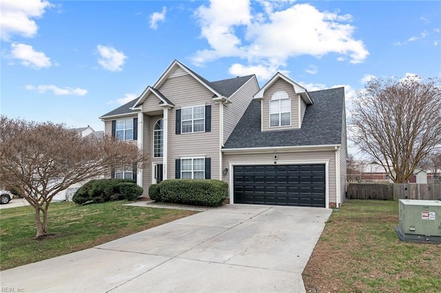 traditional-style home featuring driveway, a shingled roof, an attached garage, fence, and a front yard