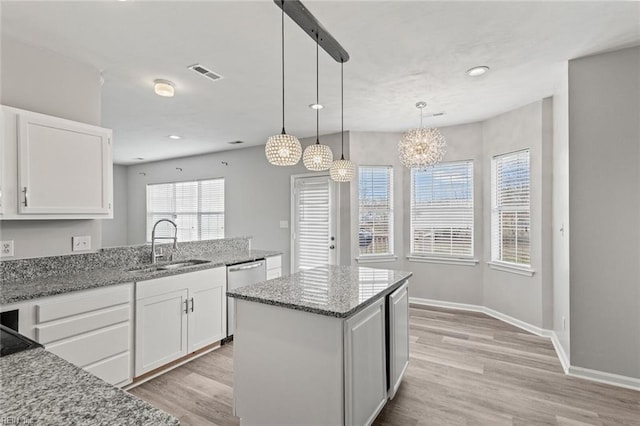 kitchen with light wood-style floors, visible vents, light stone counters, and white cabinetry