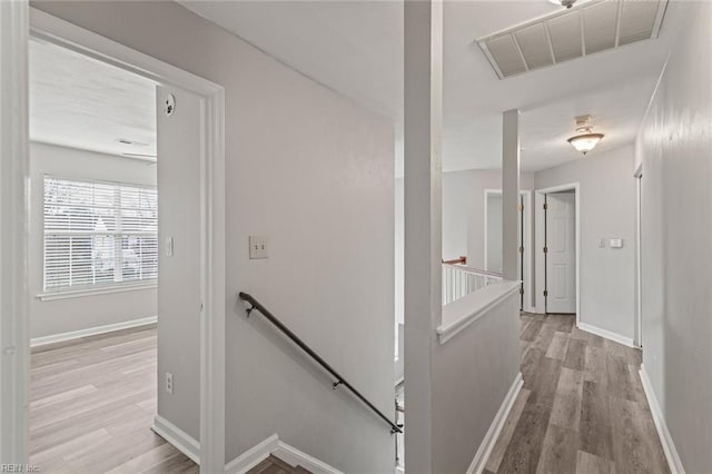 hall featuring visible vents, light wood finished floors, an upstairs landing, and baseboards