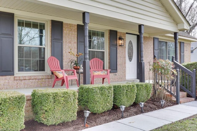 doorway to property with covered porch and brick siding