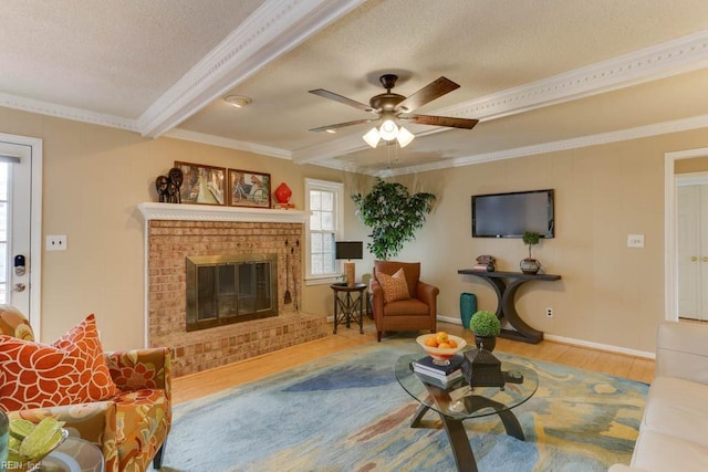 living room featuring wood finished floors, beamed ceiling, crown molding, a textured ceiling, and a fireplace