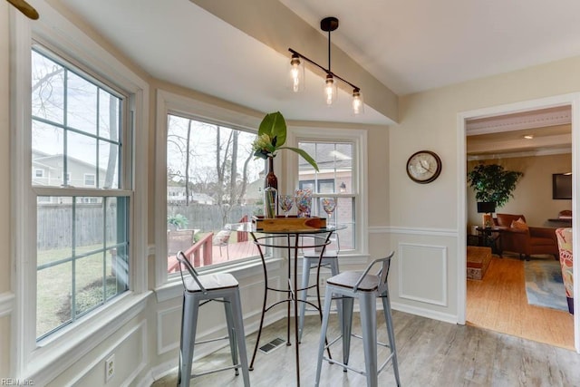 dining room featuring a wainscoted wall, wood finished floors, a wealth of natural light, and a decorative wall