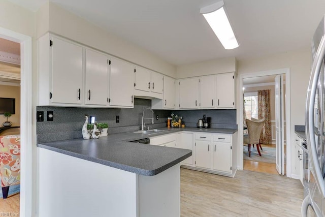 kitchen featuring light wood-style floors, tasteful backsplash, white cabinets, and a sink