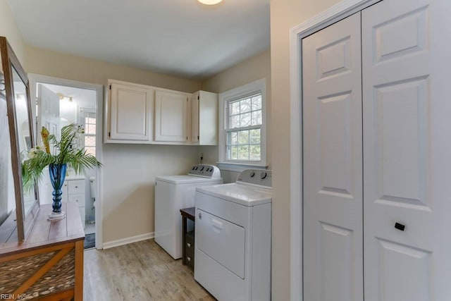 washroom with light wood finished floors, washer and clothes dryer, cabinet space, and baseboards