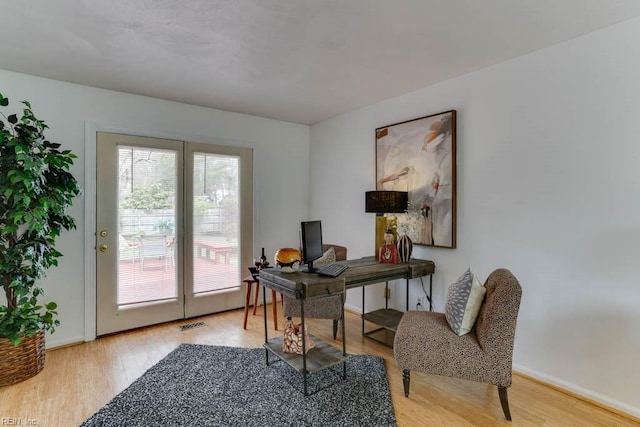 home office featuring visible vents, light wood-style flooring, and baseboards