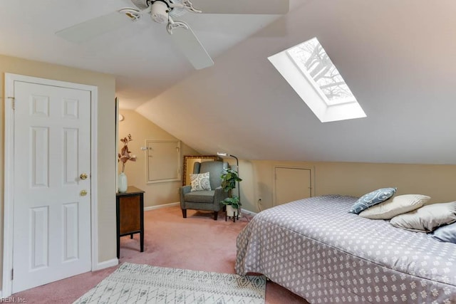 carpeted bedroom featuring vaulted ceiling with skylight, ceiling fan, and baseboards