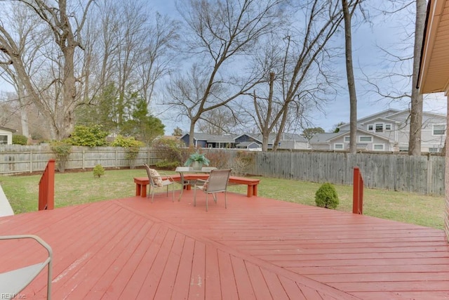 wooden deck featuring outdoor dining space, a fenced backyard, a lawn, and a residential view