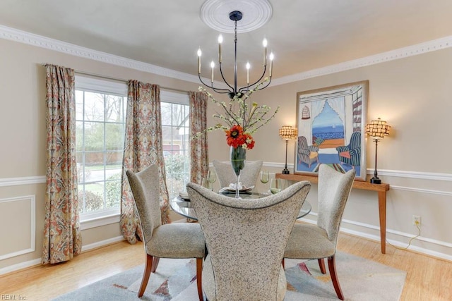 dining room featuring a notable chandelier, crown molding, baseboards, and wood finished floors