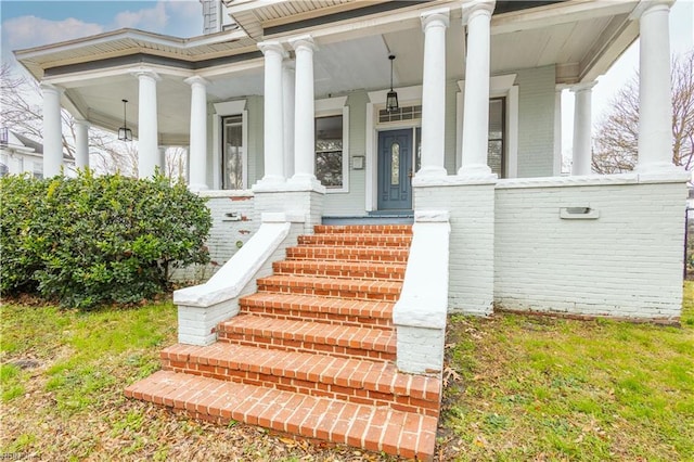 property entrance with a porch and brick siding