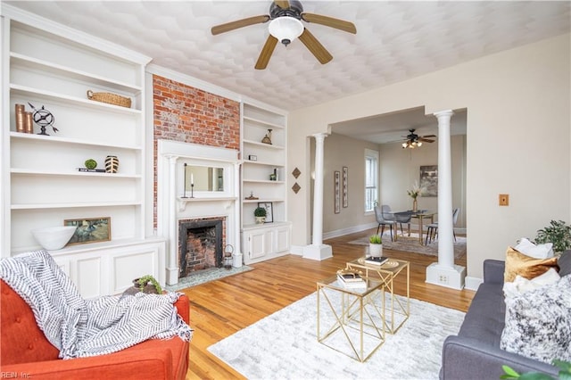 living room with a fireplace, wood finished floors, decorative columns, and baseboards