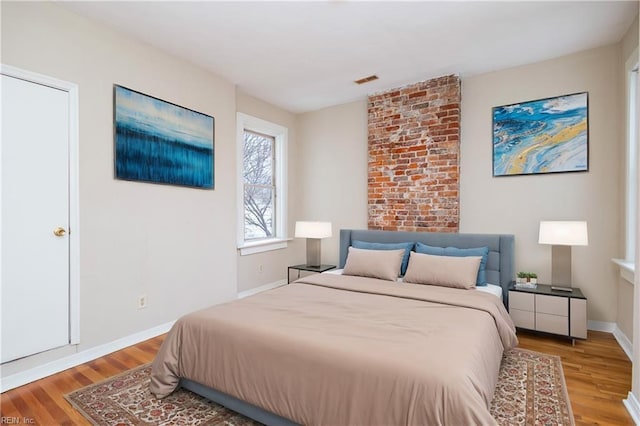 bedroom with visible vents, baseboards, and wood finished floors