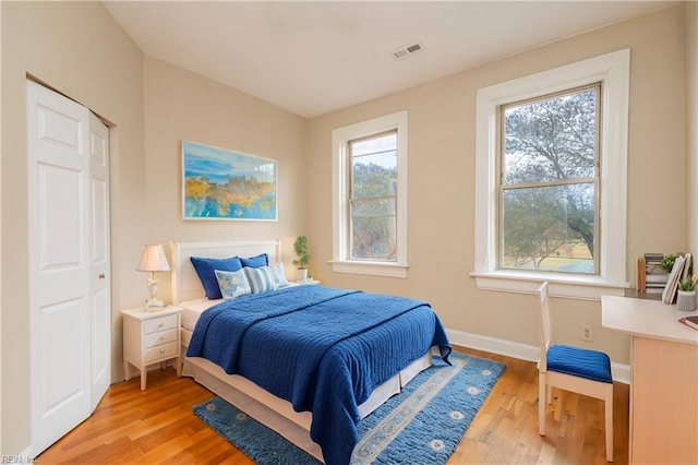 bedroom with multiple windows, visible vents, and light wood-style floors