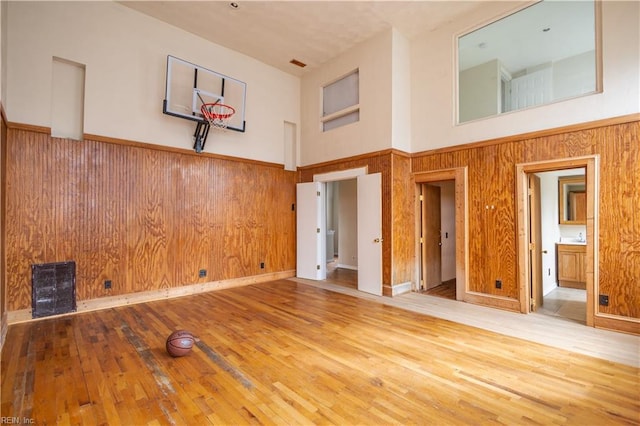 empty room with a towering ceiling, wood walls, and hardwood / wood-style flooring