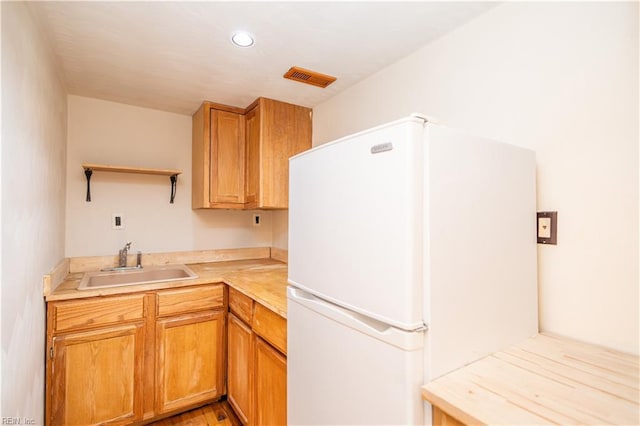 kitchen featuring open shelves, light countertops, visible vents, freestanding refrigerator, and a sink