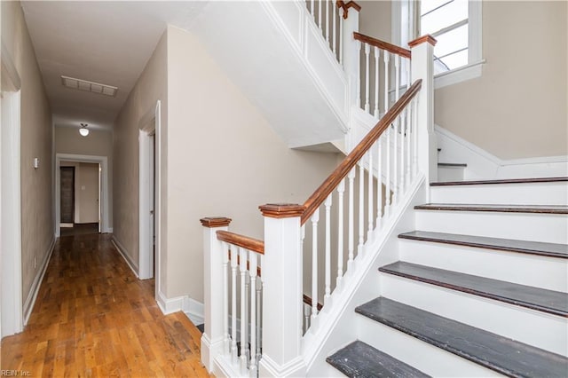 staircase with wood finished floors, visible vents, and baseboards