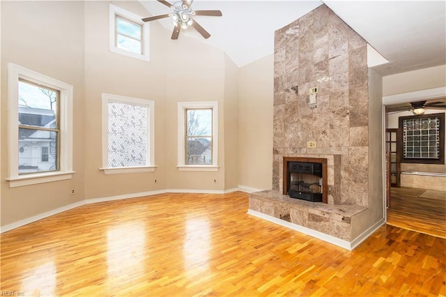 unfurnished living room featuring a ceiling fan, a tiled fireplace, and wood finished floors