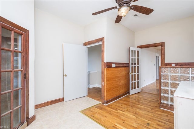 interior space featuring baseboards, visible vents, a ceiling fan, wood finished floors, and french doors