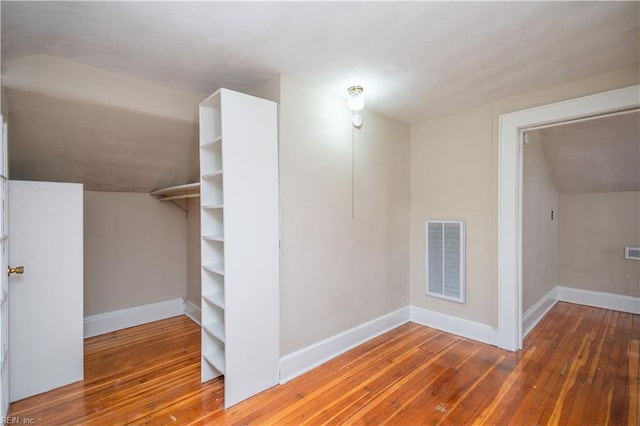 interior space featuring lofted ceiling, baseboards, visible vents, and hardwood / wood-style floors