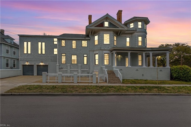 view of front of house featuring driveway, a garage, a fenced front yard, a chimney, and a porch