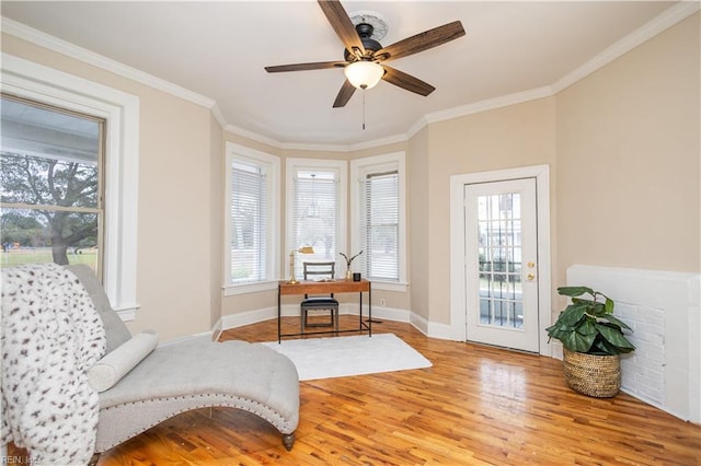 sitting room with plenty of natural light, crown molding, and wood finished floors