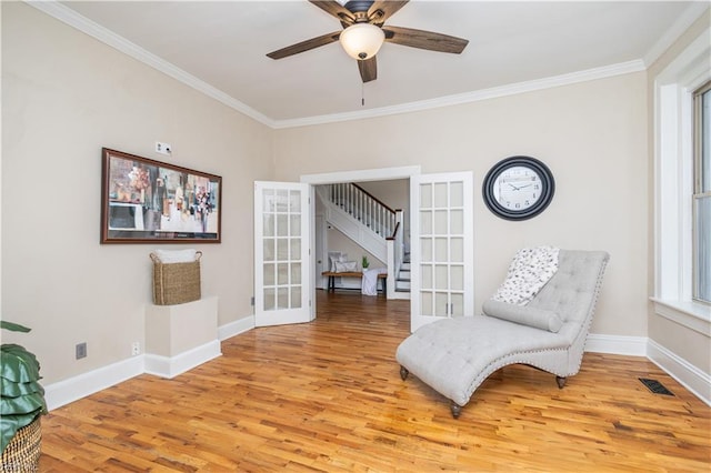 living area with crown molding, french doors, and light wood-style floors