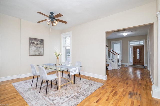 dining area featuring stairs, a wealth of natural light, baseboards, and wood finished floors