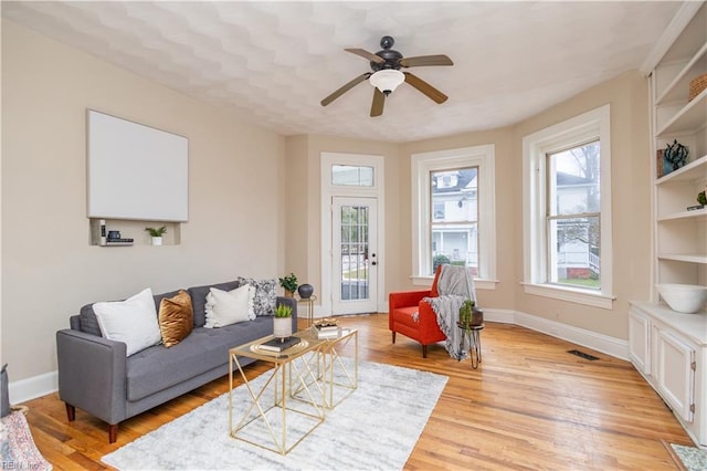 living area with visible vents, ceiling fan, light wood-style flooring, and baseboards