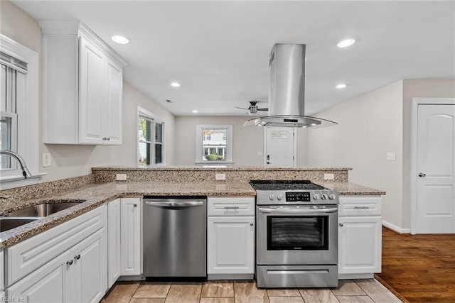 kitchen with appliances with stainless steel finishes, white cabinetry, a sink, and island range hood