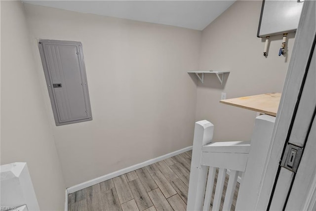 laundry area featuring electric panel, baseboards, and wood finished floors