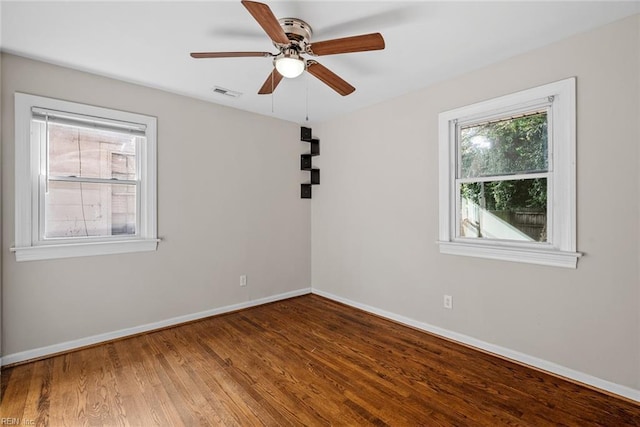 empty room featuring baseboards, visible vents, ceiling fan, and wood finished floors